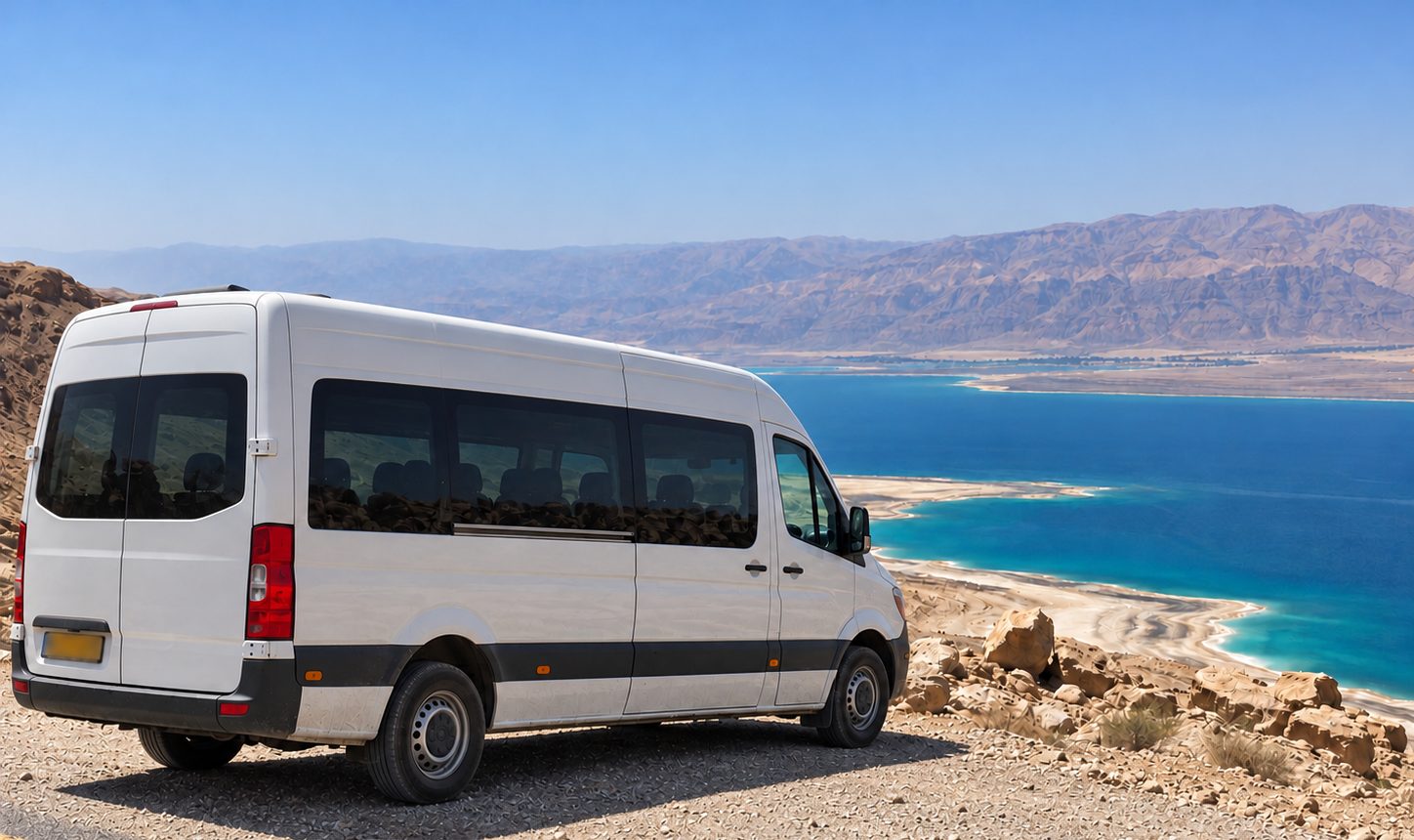 White minibus parked at a scenic overlook above the Dead Sea